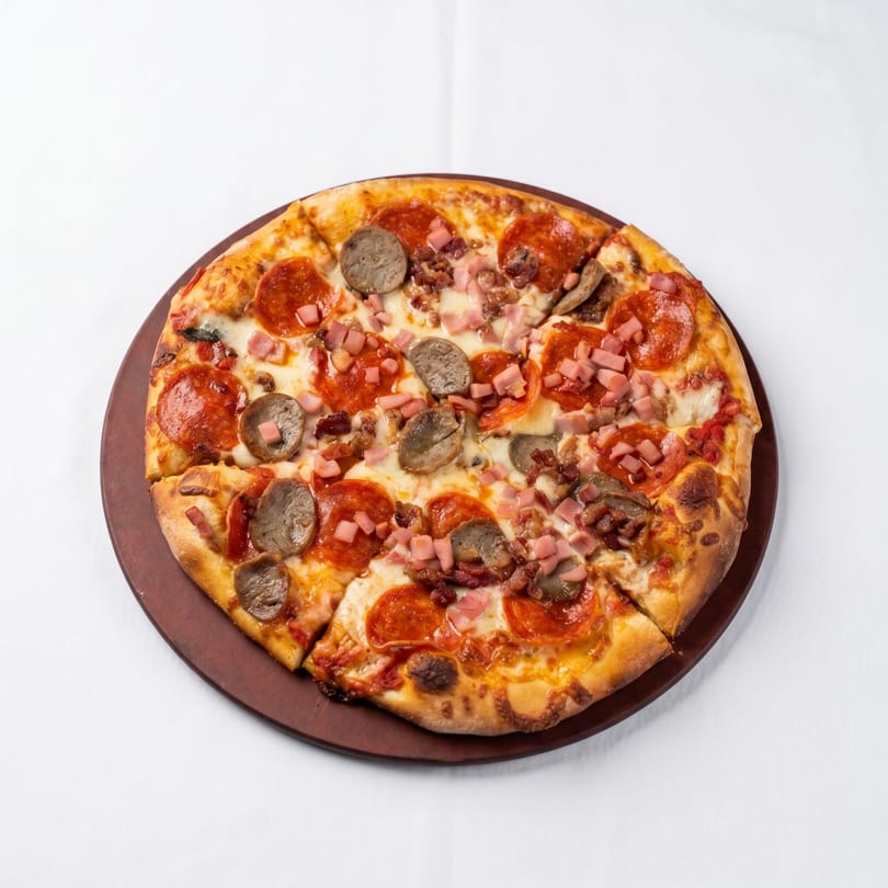 A whole meat lover's pizza with pepperoni, sausage, ham, and bacon on a wooden board.